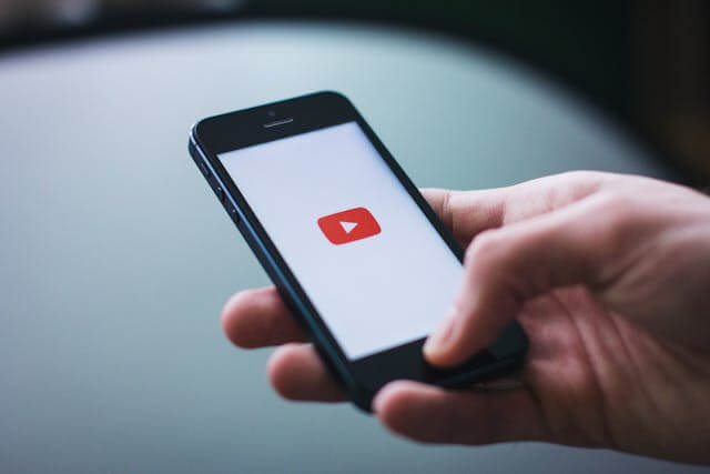 Small business owner recording a how-to video using a smartphone for YouTube Shorts.