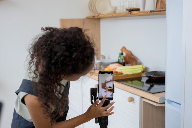 Woman filming a product demonstration in her kitchen with a smartphone