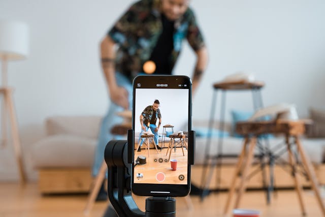 Person filming promotional video with phone on tripod in a small office