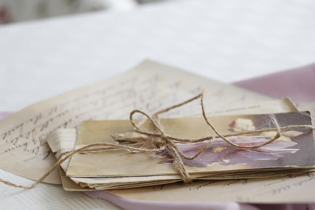 A stack of handwritten letters tied with twine on a white table, evoking personalized, heartfelt communication