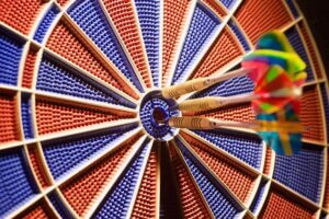 Three darts hitting the bullseye on a colorful dartboard