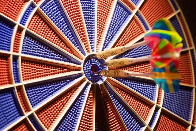 Three darts hitting the bullseye on a colorful dartboard