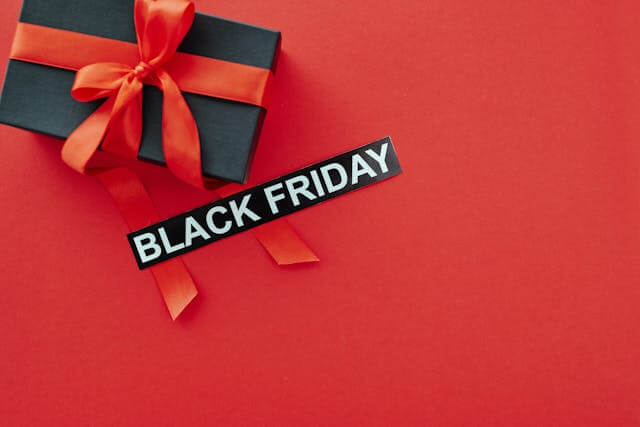 Black gift box with red ribbon and “Black Friday” label on red background illustrating promotional urgency for Denton, Dallas, Abilene and North Texas businesses
