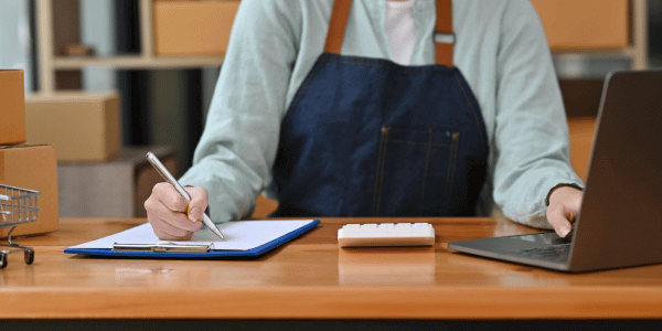 Small business owner writing marketing strategy while working on a laptop