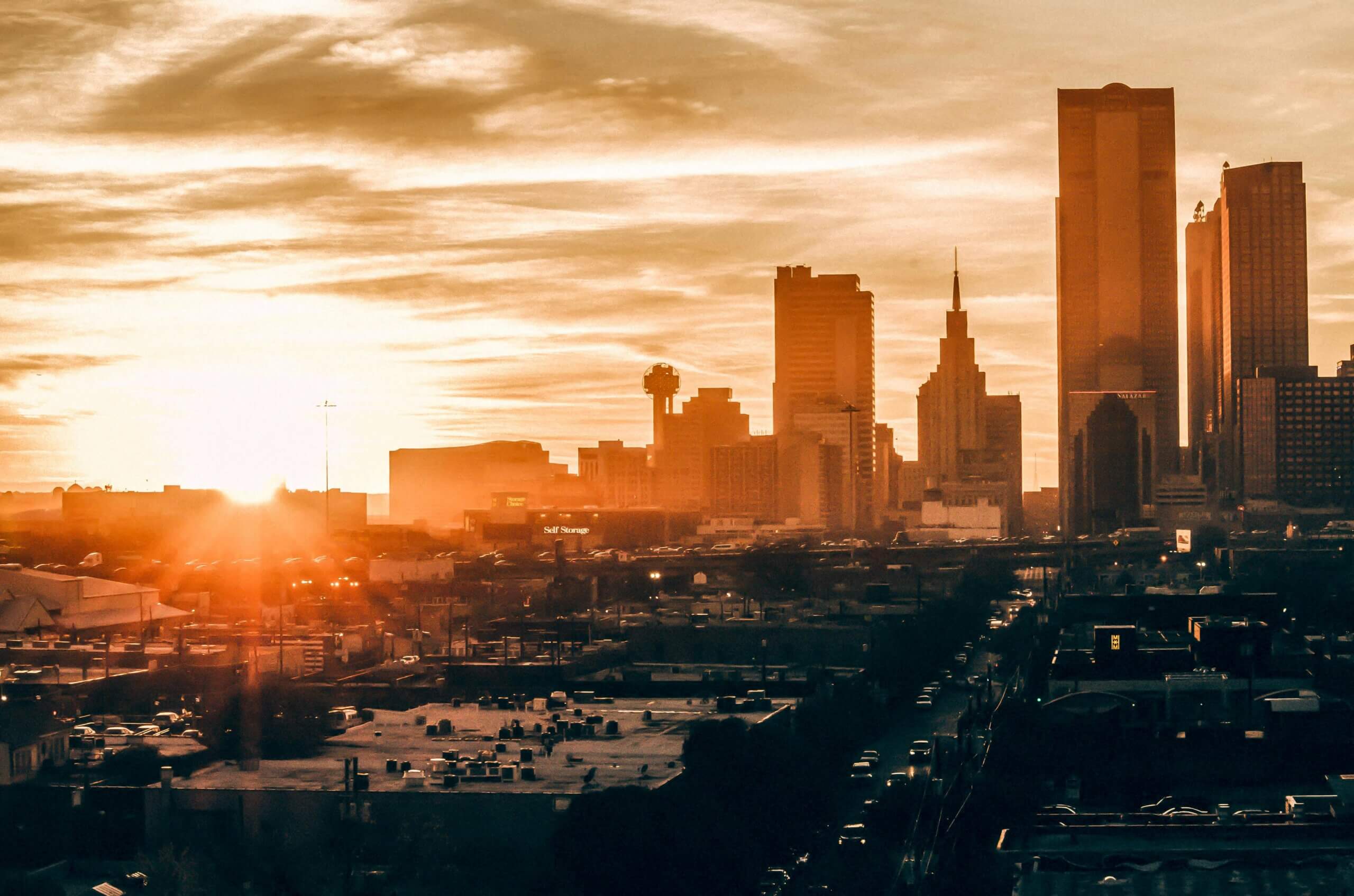 Dallas skyline at sunset with downtown buildings silhouetted against the sky.