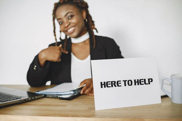 Business professional with a sign that says Here to Help, representing helpful engagement in Facebook Groups